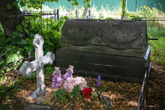 Dos tumbas con cruz y flores y sarcófago piedra negra cementerio soleado de verano