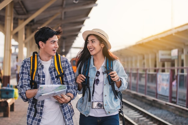 Dos turistas asiáticos con mochilas Viaje en tren en la estación de tren con un viajero, estilo vintage.