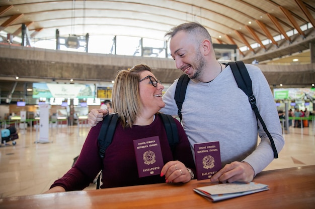 Dos turistas italianos con pasaportes en mano en el aeropuerto se miran viajeros enamorados