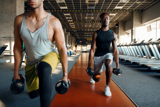 Dos varones haciendo ejercicio con pesas, entrenamiento en el gimnasio