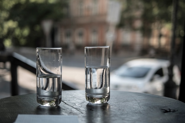 Dos vasos de agua están parados sobre una mesa en un restaurante en el fondo de las calles de la ciudad