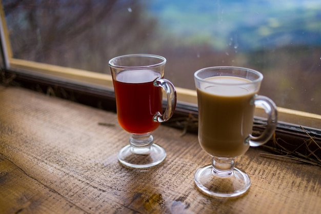 Dos vasos de bebida caliente roja y leche en las montañas