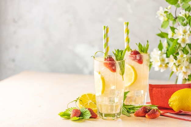 Dos vasos de bebida refrescante helada fría con limón y fresa.