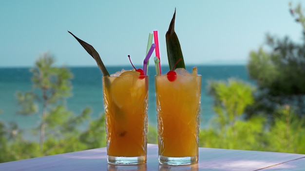 Dos vasos de bebidas de frutas heladas en tiempo de vacaciones de fondo del mar