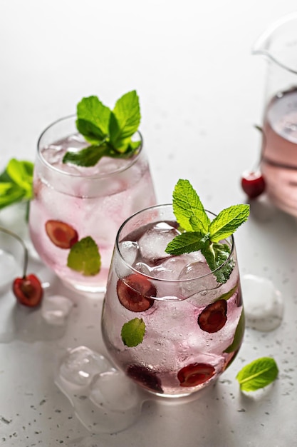 Dos vasos de bebidas heladas con cerezas y menta Orientación vertical