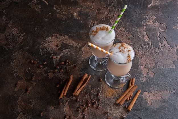 Dos vasos de café con leche en una mesa rústica de madera con granos de café y canela