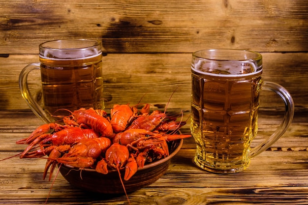Dos vasos de cerveza y cangrejos de río hervidos en la mesa de madera