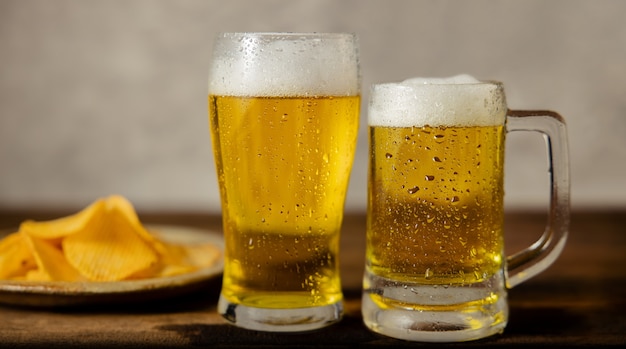 Dos vasos de cerveza y un plato de papas fritas en la mesa. Pareja o dos amigos bebiendo cerveza concepto