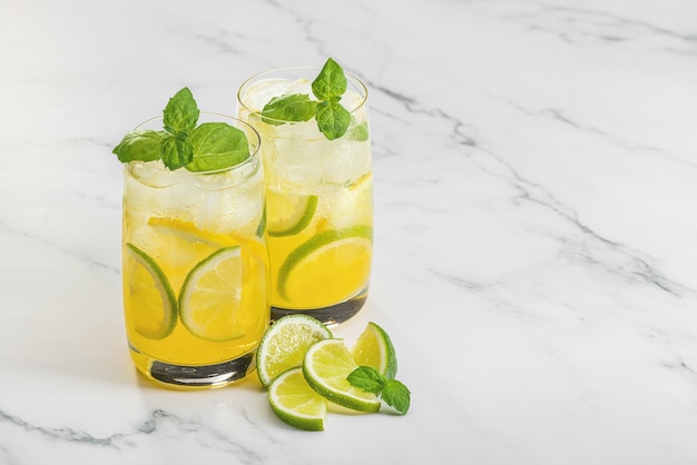 Foto dos vasos de cóctel refrescante con lima limón y hojas de menta verde