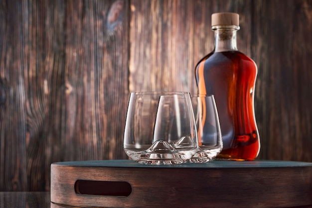 Foto dos vasos de cristal y una botella llena de whisky.