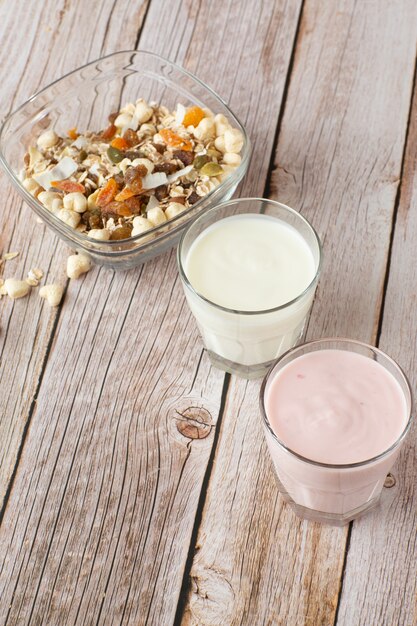 Dos vasos de fresa saludable y yogurt clásico con avena en la mesa de madera.