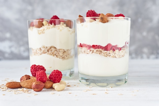 Dos vasos de granola de yogurt griego con frambuesas, copos de avena y nueces