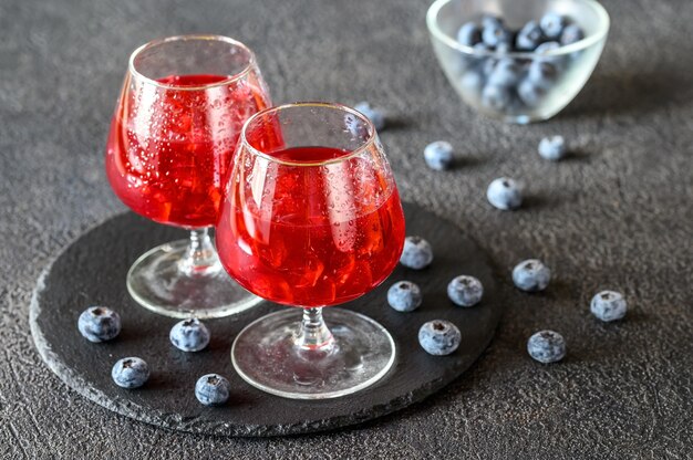 Dos vasos de jugo de arándanos con bayas frescas