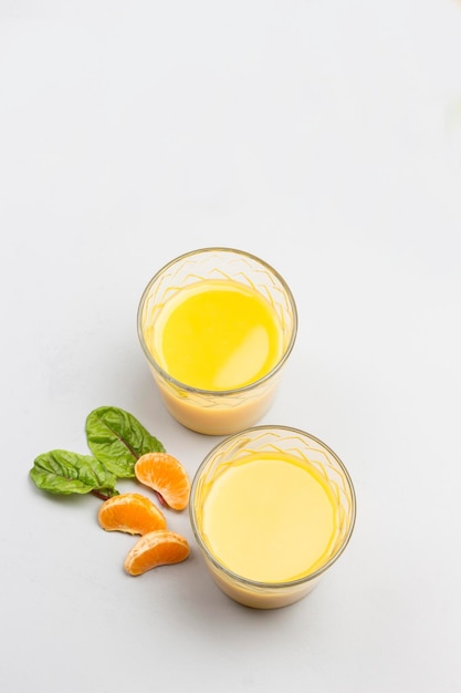 Foto dos vasos con jugo de cítricos mandarinas en la mesa