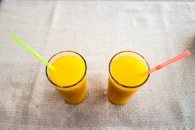 Dos vasos de jugo de naranja sobre fondo de tela de saco. Bebida saludable.