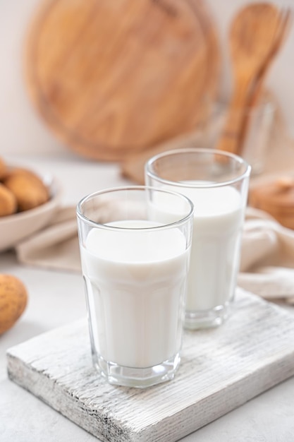 Dos vasos de leche de patata con patatas crudas sobre un fondo blanco Leche vegetariana