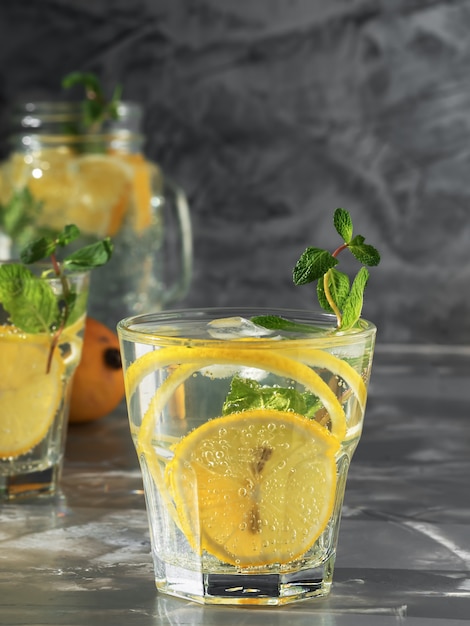 Dos vasos con limonada bebida con limón y menta.