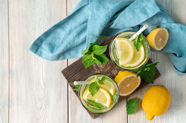 Dos vasos de limonada, limones y menta sobre un fondo claro. Vista superior, espacio de copia.