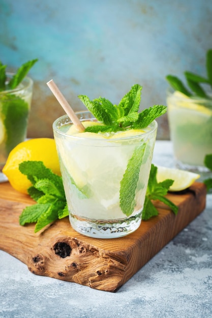 Foto dos vasos con limonada o cóctel mojito con limón y menta bebida refrescante fría o bebida con hielo sobre fondo azul rústico