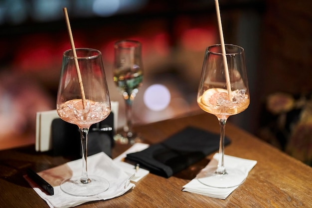 Dos vasos medio vacíos con hielo y una rodaja de naranja sobre una mesa en un bar