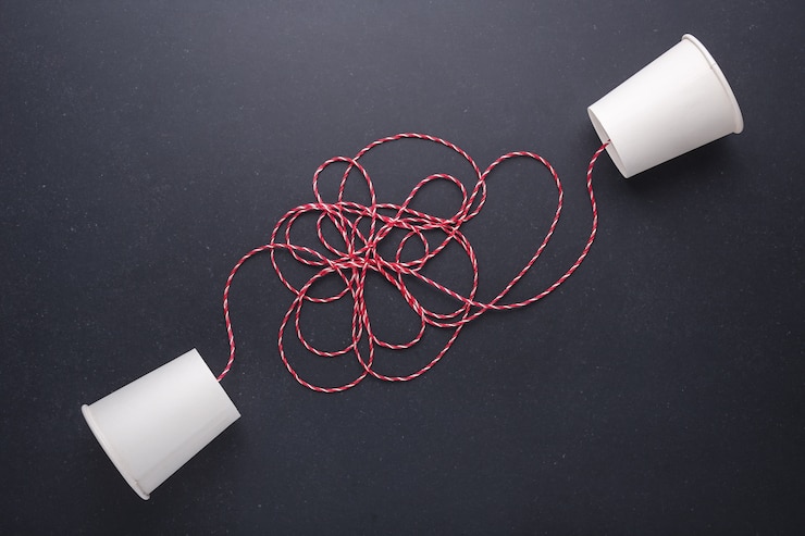 Foto dos vasos de papel blanco se conectan con cuerda roja utilizada para teléfono clásico