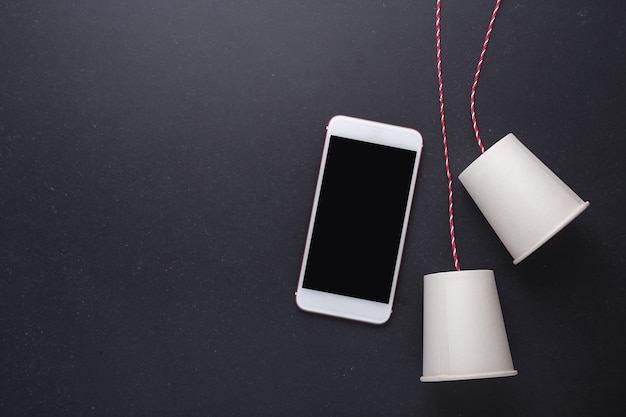 Dos vasos de papel blanco se conectan con cuerda roja utilizada para teléfono clásico