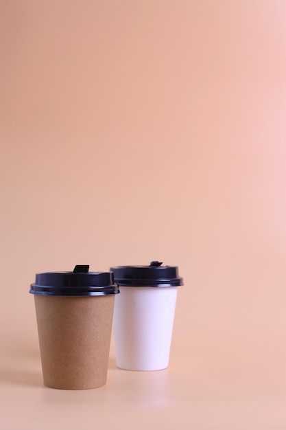 Dos vasos de papel desechables en blanco en marrón y blanco con tapa de plástico simulados. Café de poliestireno vacío