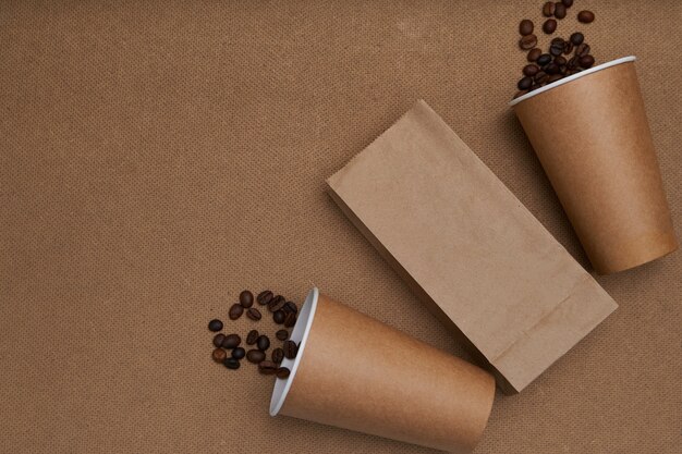 Dos vasos de papel con granos de café y un paquete.