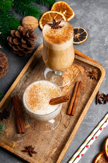 Dos vasos de ponche de huevo de bebida tradicional navideña sobre un fondo gris, foto vertical. Bebida picante a base de huevo y leche con canela, cardamomo. Foto de alta calidad