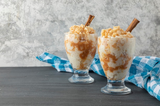 Dos vasos con postre de arroz con leche en una mesa con un mantel azul