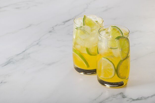 Dos vasos de refrescante limón, lima y hielo.