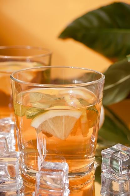 Dos vasos de té frío con hielo y fruta de limón.