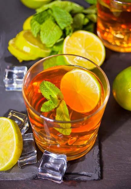 Dos vasos de té frío con hielo y fruta de limón.