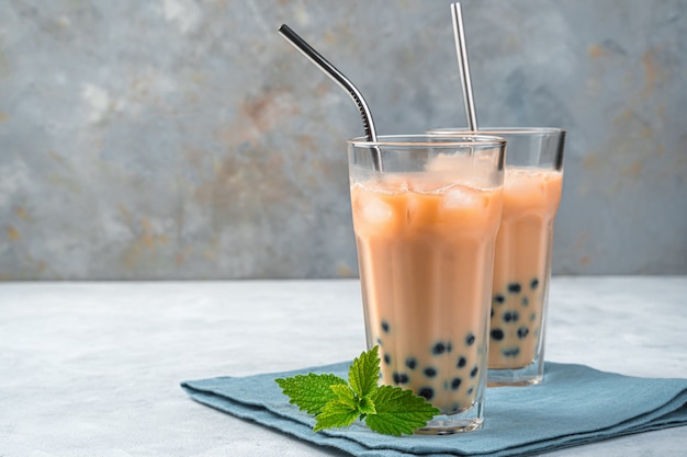 Dos vasos de té de tapioca en una pared gris con espacio de copia. Té de burbujas de leche casero con perlas de tapioca. Bebida refrescante taiwanesa.