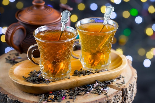 Dos vasos de té con una tetera sobre una mesa de madera