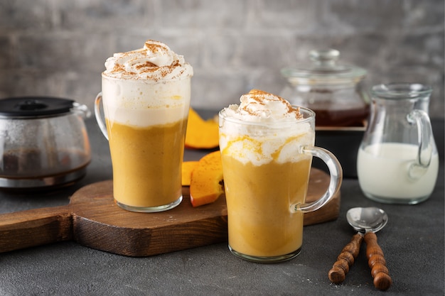 Dos vasos de vidrio con capuchino de calabaza con especias sobre superficie gris oscuro