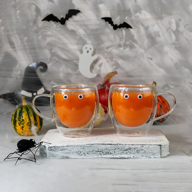 Dos vasos de vidrio con jugo de calabaza en el fondo de las calabazas de Halloween.