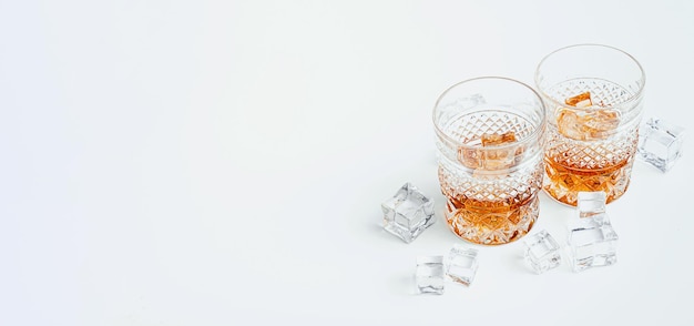 Dos vasos de whisky con hielo sobre un fondo blanco con lugar para texto