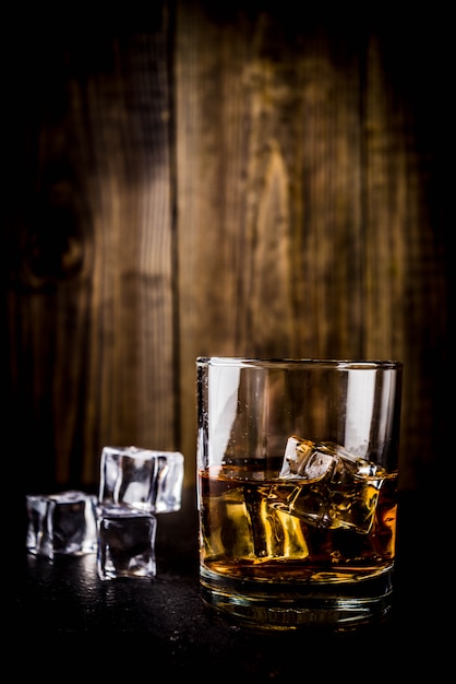 Dos vasos de whisky en la mesa de madera oscura, con cubitos de hielo,