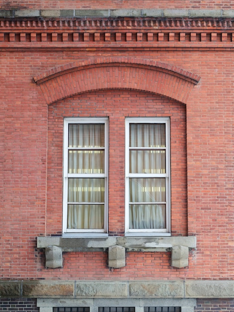 Foto dos ventanas en una pared de ladrillo rojo.