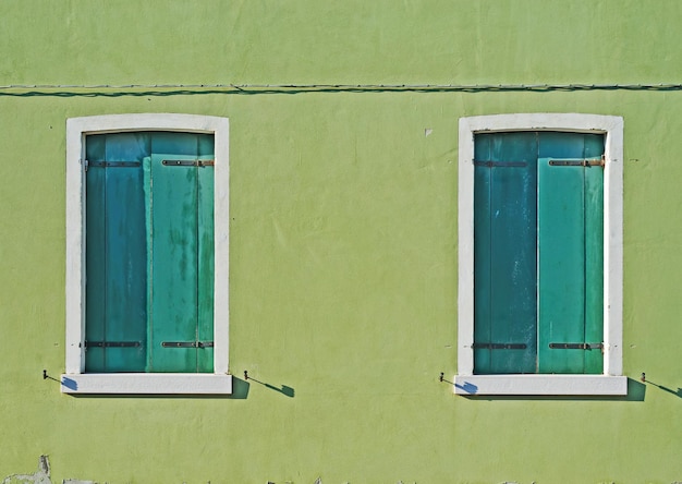 Dos ventanas verdes en una pared verde