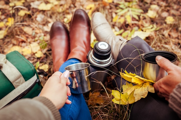 Dos viajeros tomando té en el bosque de otoño