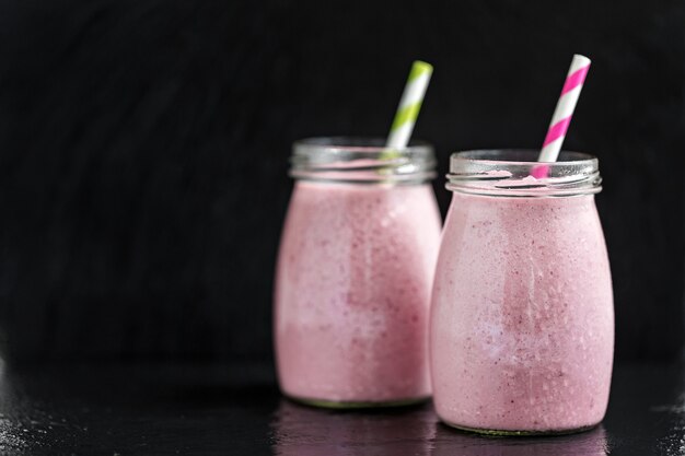 Dos vidrios con los smoothies rosados de la baya con la pasa y el arándano, foco selectivo.