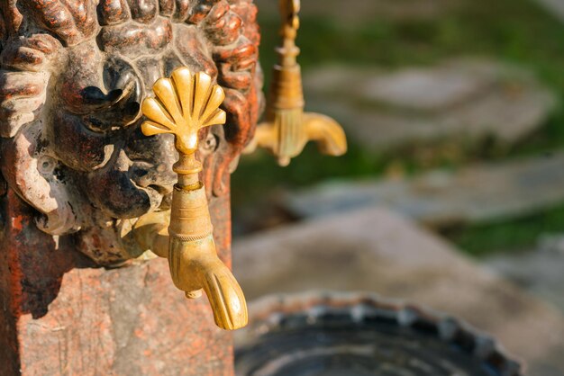 Foto dos viejos grifos de agua de metal de color dorado en la pared de piedra roja