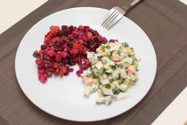 Foto dos vinagretas de ensalada diferentes y olivier en un plato blanco