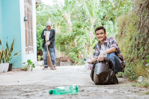 Dos voluntarios adolescentes felices recogiendo basura