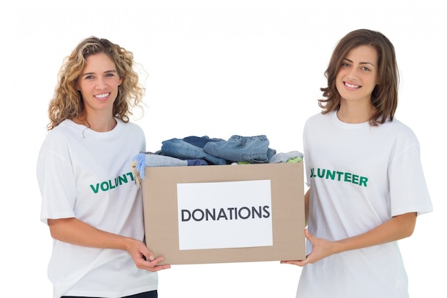 Foto dos voluntarios alegres llevando caja de donación de ropa