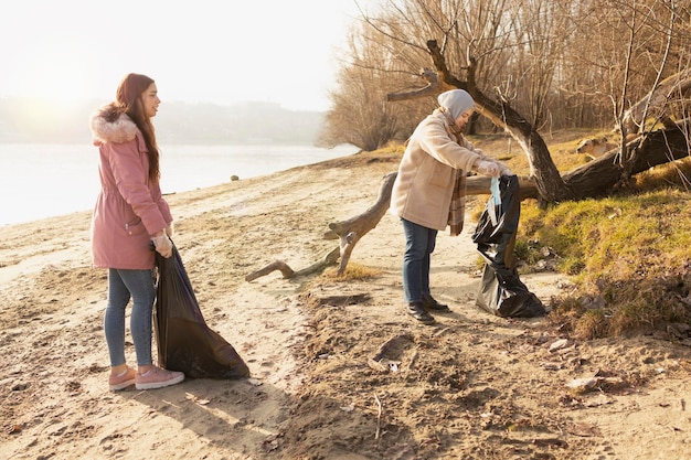 Dos voluntarios limpiando la basura de la orilla de un río