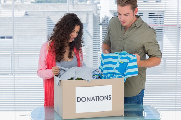 Foto dos voluntarios sacando la ropa de una caja de donación