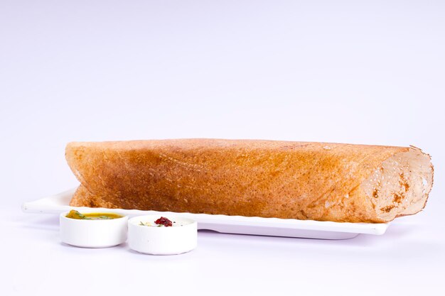 Dosa Ghee asado Dosafamoso artículo de desayuno del sur de la India hecho en una sartén de hierro fundido de manera tradicional y dispuesto sobre una base blanca con guarnición sobre un fondo blanco aislado